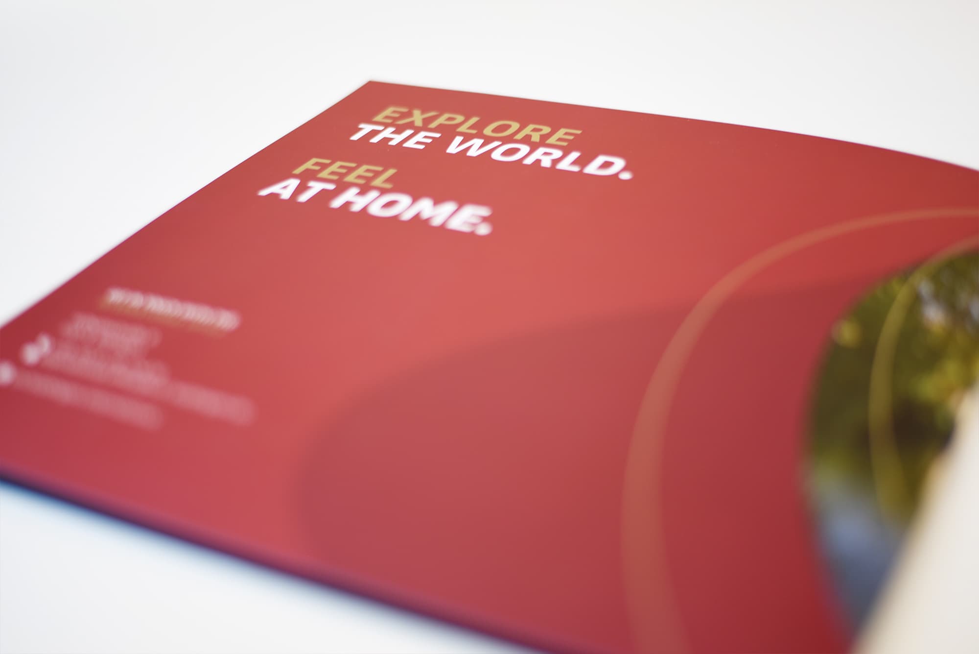 Ein rotes, quadratisches Heft mit der Aufschrift "Explore the world. Feel at home."